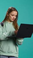 vertical alegre mulher adicionando Forma de pagamento método em local na rede Internet usando computador portátil, desfrutando vendas período, estúdio fundo. menina fazendo compras em Internet, digitando crédito cartão em formação em caderno, Câmera b video