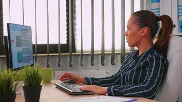 Business woman typing on computer in modern office room. Hispanic entrepreneur working in professional workspace, in personal corporate company writing on computer keyboard looking at desktop video