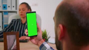 Immobilized financial manager in wheelchair using smartphone with greenscreen for videomeeting. Paralysed disabled freelancer looking at display with chroma key mockup talking with remotely colleagues video