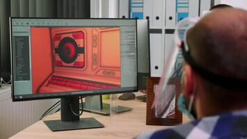 Immobilized game developer sitting in wheelchair with protection face mask working at project from new normal studio office during covid-19 pandemic. handicapped man respecting social distance. video