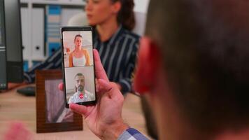 Entrepreneur talking on videocall with company manager and executive administrator sitting on desk in corporate building office using smartphone. Financial businessman using modern technology. video