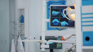 Close up of medical orthodontist display with x ray images on it. Empty professional hospital stomatology chair with nobody in it. Close up revealing shot. Modern dentist equipment video