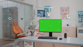 Nobody in dental cabinet with green screen on computer for teethcare. Empty dentist office with isolated background and mockup template on monitor for chroma key. Oral care and dentition video