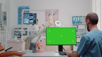 Dental assistant using monitor with horizontal green screen in dentist office. Oral care specialists working with teethcare equipment and chroma key for isolated background in cabinet. video