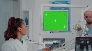 Close up of dentist looking at monitor with green screen for teeth scan examination in dental office. Dentistry specialist using chroma key with mockup template and isolated background video