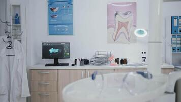 Empty orthodontic stomatology office prepared for teeth treatment after medical dental diagnosis. Doctor cabinet equipped with tooth instruments for oral care. Dentistry xray images on monitor video