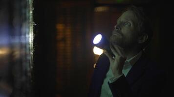 Man in suit spies at night Investigating bank vault safe holding a flashlight in dark room video