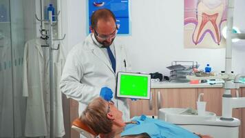 stomatolog ser på grön skärm läsplatta medan tala med patient. man förklara använder sig av övervaka med grön krom nyckel isolerad krom pc nyckel attrapp grönskärm visa mock-up pekskärm video