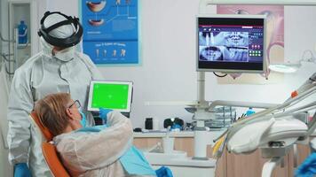 Dentist with face shield pointing at green screen display during coronavirus epidemic. Explaining using monitor with chroma key izolated chroma pc key mockup greenscreen display mock-up touchscreen video