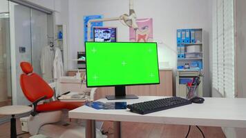 Computer with chroma key pc desktop placed in front of camera in empty equipped stomatological room. Stomatology clinic with nobody in it prepared for patient using green screen, mockup display video