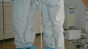 Stomatology team of dentists holding tablet for teethcare examination standing in dentistry office with ppe suits. Orthodontic specialists using technology discussing oral procedure video