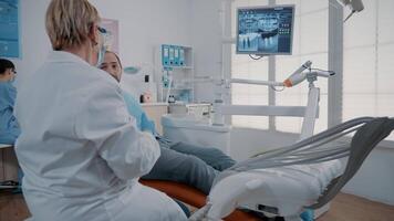 Orthodontist pointing at teeth radiography on monitor to show caries diagnosis to patient in pain. Dentist explaining x ray scan and stomatological procedure to cure toothache. video