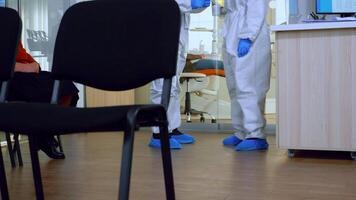 Orthodontics doctors with face shield and ppe suit discussing in reception about teeth x-ray while patient waiting during global pandemic. Concept of new normal dentist visit in coronavirus outbreak. video