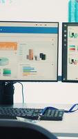 Vertical Empty business corporation workstations in a modern boardroom, office coworking space used in monitoring workflow and current firm situation. Big screen running important infographics. Camera A. video