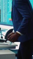 Vertical Chief financial officer examining capital funds and revenue data on annual reports in an office with a big screen, reviewing profit increase and budget allocation for a project. Camera A. video