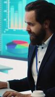 Vertical Corporate employee looking into project details and timetables in open coworking space, establishing budget and operations to accomplish goals in a competitive environment. Camera A. video