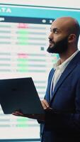 Vertical Business investor reviewing latest budgeting plans on a big screen with data reports, collecting details about financial updates to ensure global expansion. Shareholder making decisions. Camera A. video
