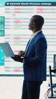 Vertical Chief financial officer studying capital funds and revenue data on big screen, verifying annual reports and budget allocation for a project. Looking for ways to increase profit. Camera A. video
