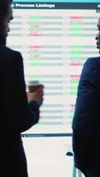 Vertical General director discussing with an investor to increase funding for a project, presenting performance metrics and annual data on a big screen. Business associates share strategies. Camera A. video