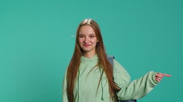 Upbeat woman pointing with finger in all directions, doing advertising, talking with audience. Young teenager doing presentation, showing copy text, studio backdrop, camera A video