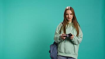 Young gamer girl holding controller, focused on finishing difficult videogame level. Woman gaming with gamepad and solving quests, isolated over studio backdrop, camera B video