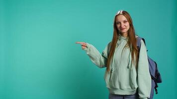 Portrait of cheerful person pointing finger towards empty space, doing advertising. Happy lady doing presentation, showing copy text, isolated over studio background, camera B video