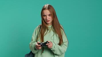 Euphoric woman playing intense gaming console game, celebrating win, studio background. Ecstatic young girl using controller, excited after being victorious in videogame, camera A video