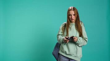Young girl spamming controller buttons, disappointed after receiving game over screen. Woman upset after losing videogame, playing with gamepad, studio background, camera B video