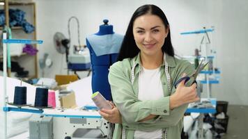 Portrait of a beautiful seamstress carrying a tape measure and working in a textile factory video