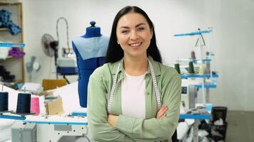 Portrait of a beautiful seamstress carrying a tape measure and working in a textile factory video