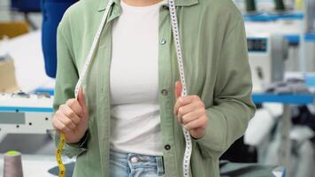 Close up of a seamstress carrying a tape measure and working in a textile factory video