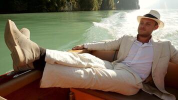 A welldressed man is leisurely relaxing on a boat, enjoying the tranquil view around him video
