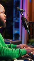Vertical Young songwriter playing piano and singing on microphone, recording his new music and mixing the tunes on digital software. Musician composer producing soundtracks with modern gear. Camera A. video