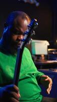 Vertical Producer creating a track by playing acoustic guitar in home studio, recording songs and singing on microphone. Sound engineer mixing and mastering his melody with stereo gear, soundtracks. Camera B. video