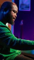 Vertical Artist playing piano electronic keyboard and recording new sounds, producing new midi controller notes in his home studio. Audio producer working with digital audio workstation software. Camera A. video