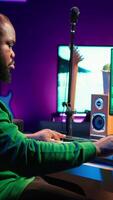 Vertical Audio composer playing piano electronic keyboard to create a new track, adjusting volume levels on old recordings. Music producer recording sounds, plays tunes on midi controller. Camera A. video