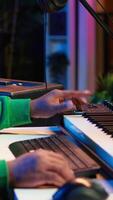 Vertical African american artist composing a new soundtrack for a project, using professional production software in home studio. Skilled creative singer producing music and adding sound effects. Camera A. video