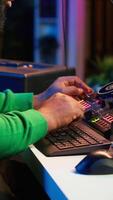 Vertical Skilled male composer producing new songs on his mixing console, operating on professional gear in home studio. Artist audio engineer twisting knobs to adjust sound levels on tracks. Camera A. video