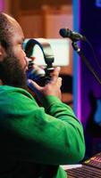 Vertical Talented musician mixing and mastering songs on a console, twisting pre amp knobs to add sound effects in post production. Producer composing tracks for album, working in home studio. Camera A. video