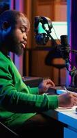 Vertical Songwriter taking notes to create new tracks for an album in his home studio, writing lyrics and harmonic elements before recording his song and editing on software, acoustical engineering. Camera A. video