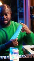 Vertical Skilled performer explaining sheet with musical notes on online tutorial, internet lessons in home studio. Producer artist teaching how to read acoustical notation, playing piano. Camera A. video
