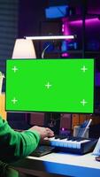 Vertical Artist plays midi controller synthesizer next to green screen layout, working on producing new music with his audio musical instruments in home studio. Musician using isolated copy space. Camera B. video