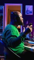 Vertical Confident songwriter performing a tune on microphone in home studio, recording his song and editing in post production. Performer artist singing aloud and using stereo equipment. Camera B. video