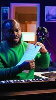 Vertical Skilled performer explaining sheet with musical notes on online tutorial, internet lessons in home studio. Producer artist teaching how to read acoustical notation, playing piano. Camera B. video