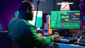 Creative songwriter recording new tracks with microphone and midi controller, playing piano notes in home studio. Skilled musician composing music with electronic keyboard and stereo gear. Camera A. video