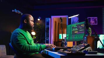 Creative songwriter recording new tracks with microphone and midi controller, playing piano notes in home studio. Skilled musician composing music with electronic keyboard and stereo gear. Camera B. video