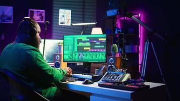 Audio technician works with recording tools in his home studio, using mixing console and pre amp knobs to add sound effects on tracks. Composer editing new tunes in post production. Camera B. video