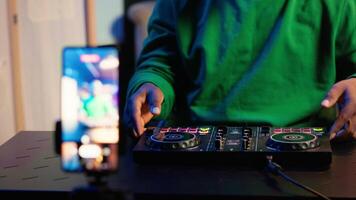 Skilled audio engineer teaching online mixing tunes lessons by using smartphone on tripod to record himself in home studio. Producer hosting a master class with soundboard console gear. Camera A. video