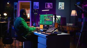 Producer composing new track with electronic gear in his home studio, creating music on mixing console and software interface. Talented artist songwriter controls panel to produce sounds. Camera B. video
