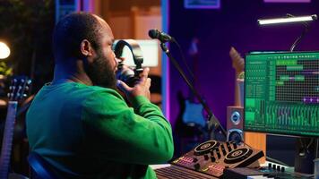 Talented musician mixing and mastering songs on a console, twisting pre amp knobs to add sound effects in post production. Producer composing tracks for album, working in home studio. Camera A. video